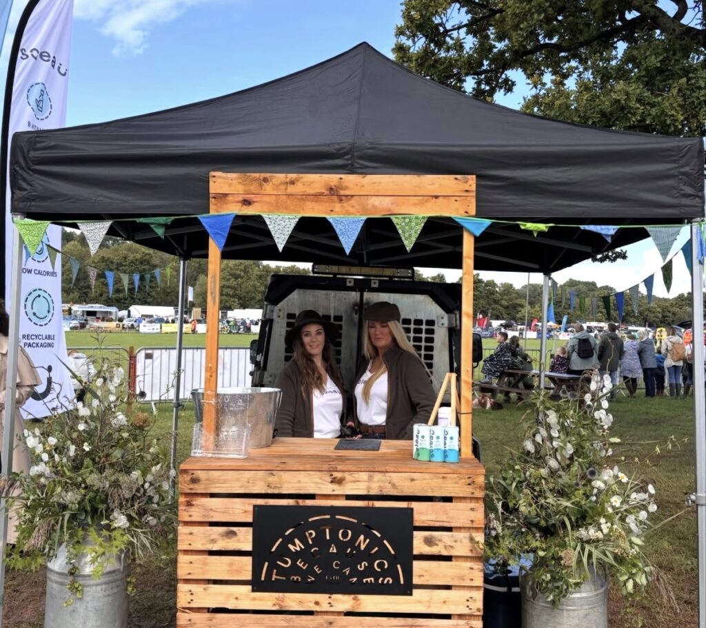 Two Ladies positioned behind the Tumptonics stand at Usk Agricultural Stand giving out spring water, Soleau, to new customers