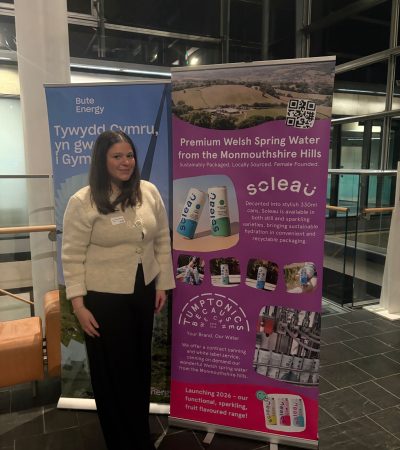 Angharad, Tumptonics Brand Ambassador, standing in front of a Soleau promotional banner at the Welsh Assembly.